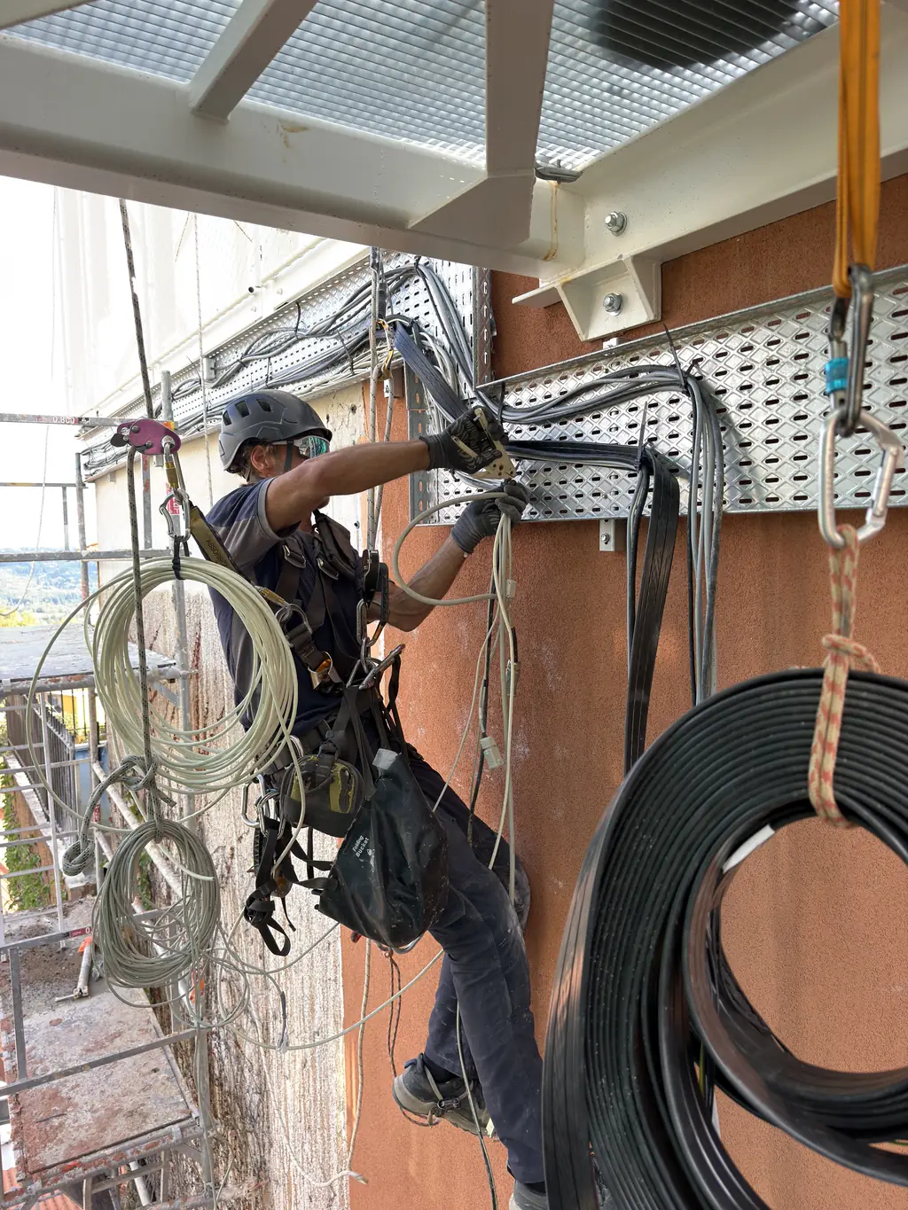 Rope access technician installing cables on a facade