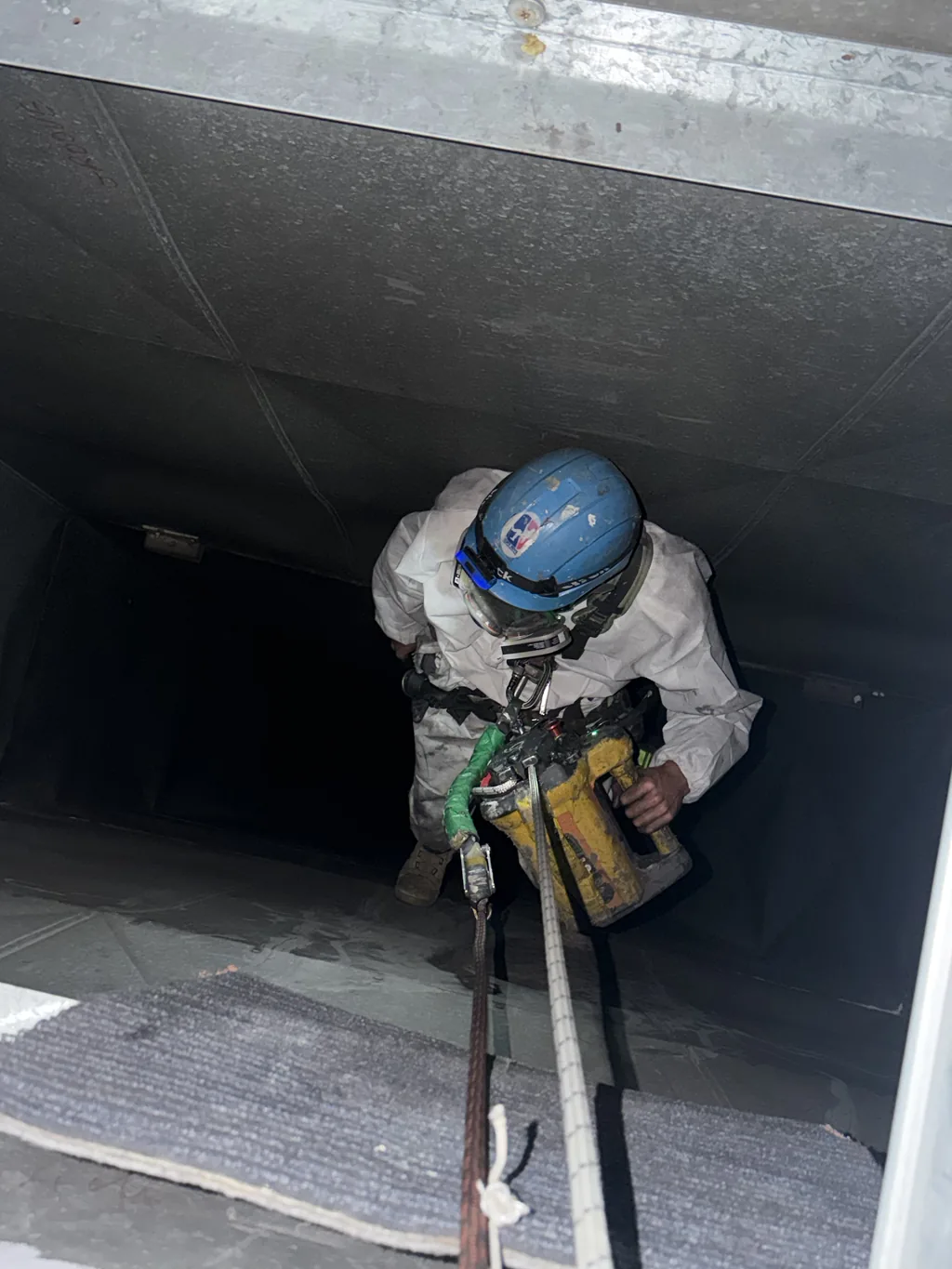 Rope access technician working inside a metal duct, confined space