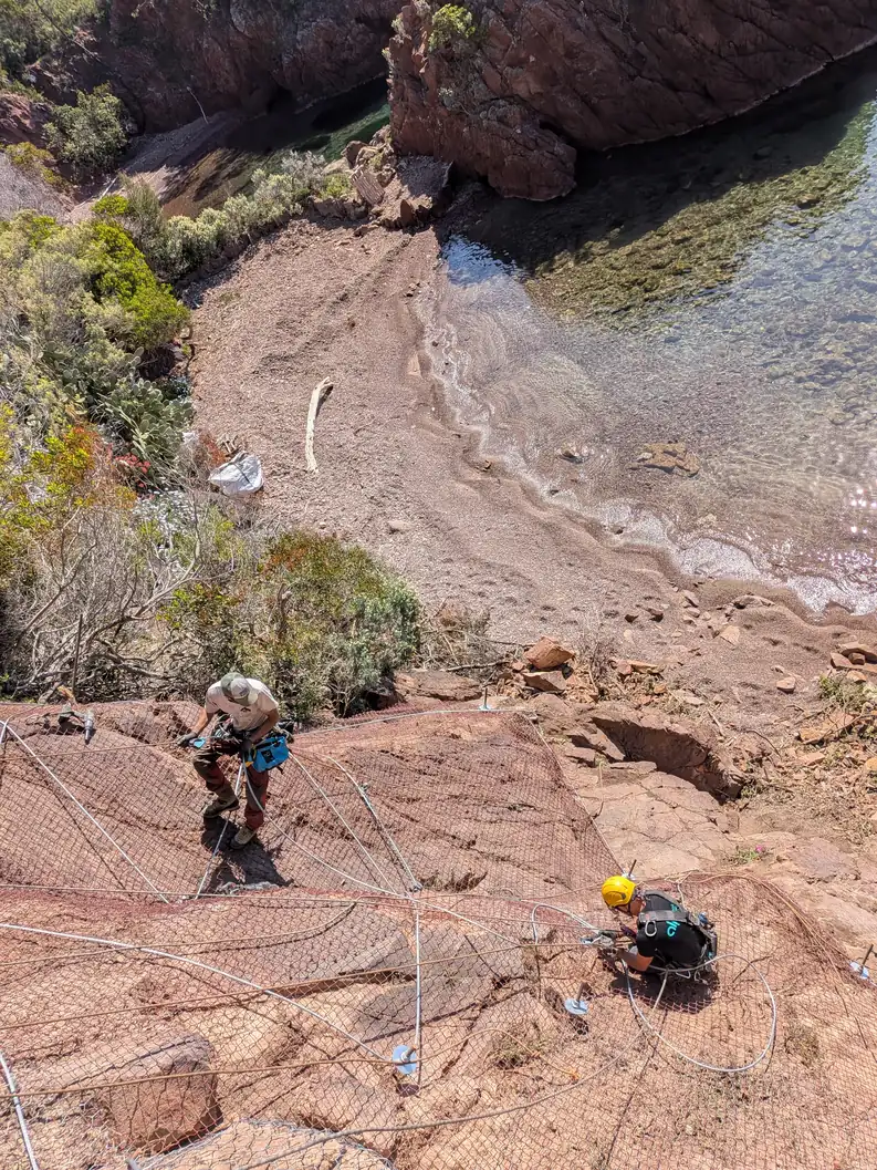 Rope access technicians on red rocks by the sea, Théoule-sur-Mer