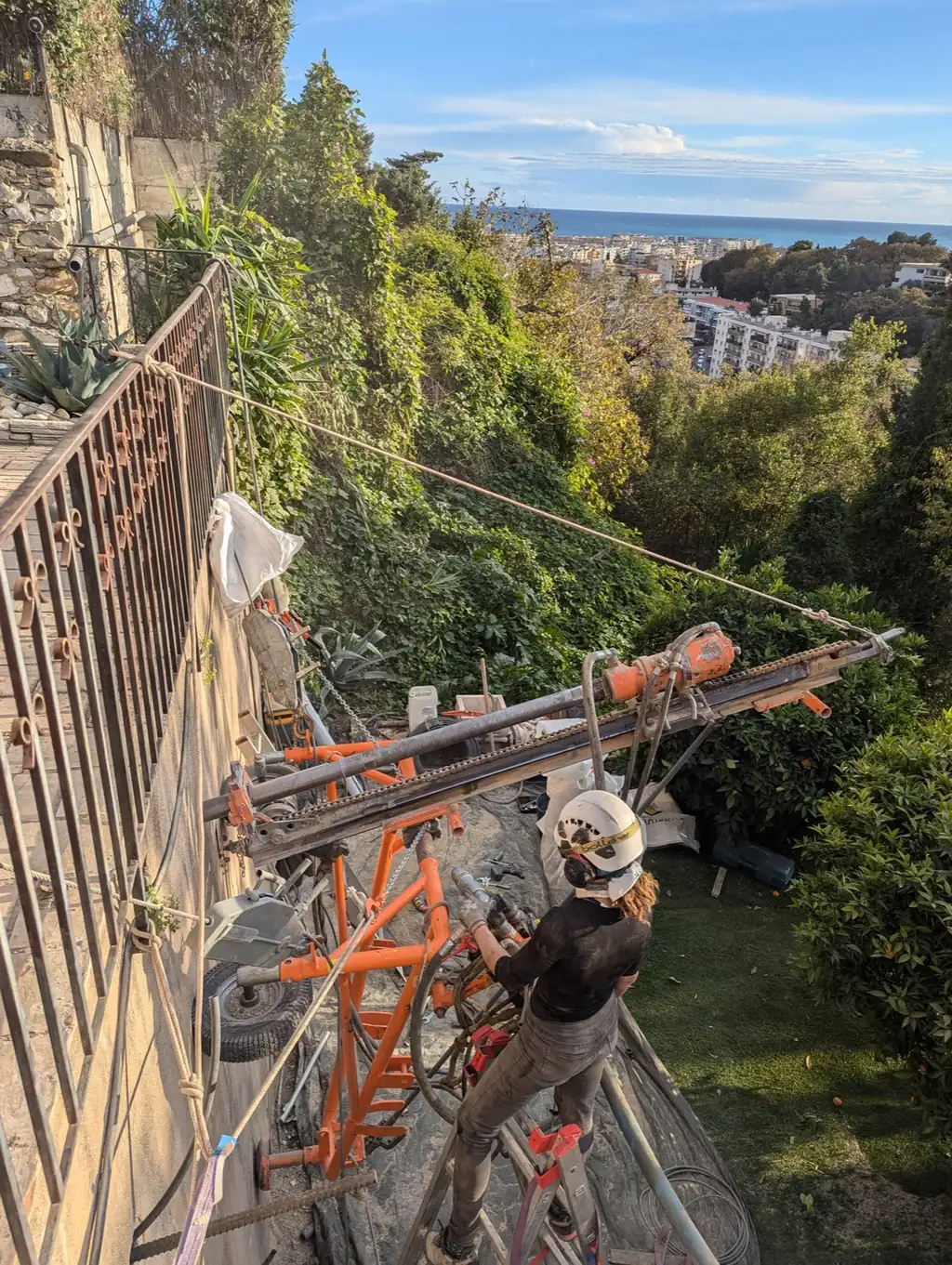 Rope access technician and drilling rig on a rock face above the town