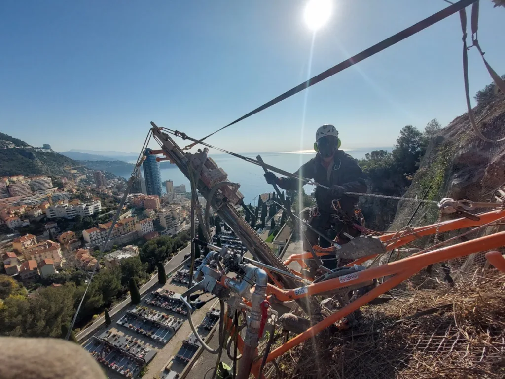 Drilling rig in position for a geotechnical anchor, above the town