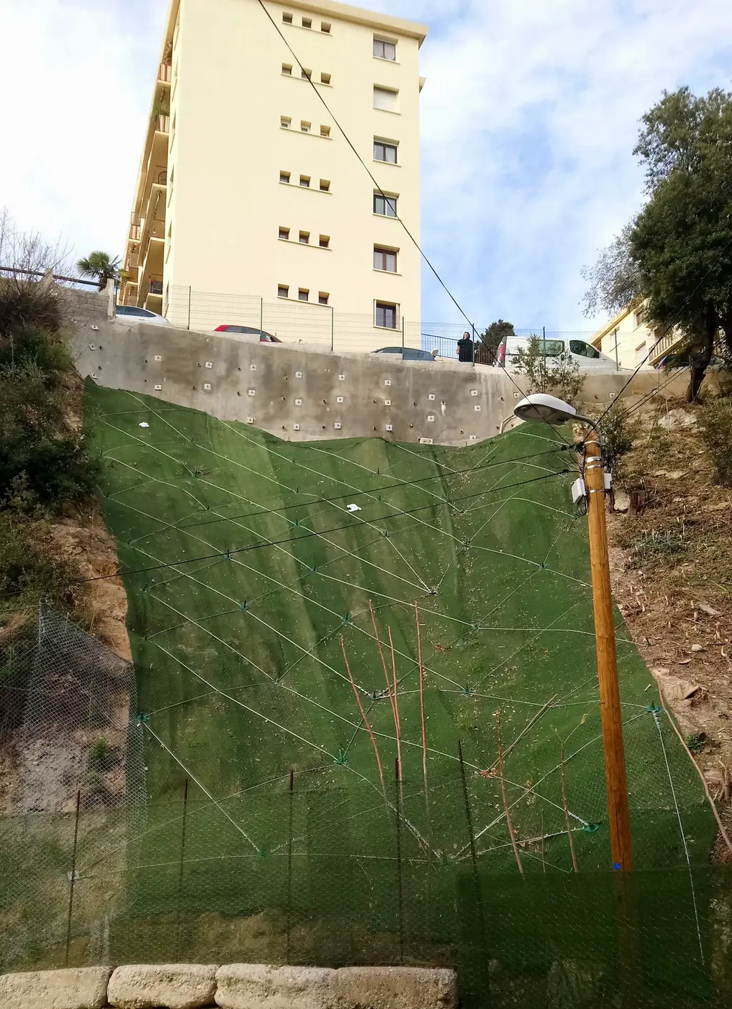 Embankment protected by geotextile and a net at the foot of a building