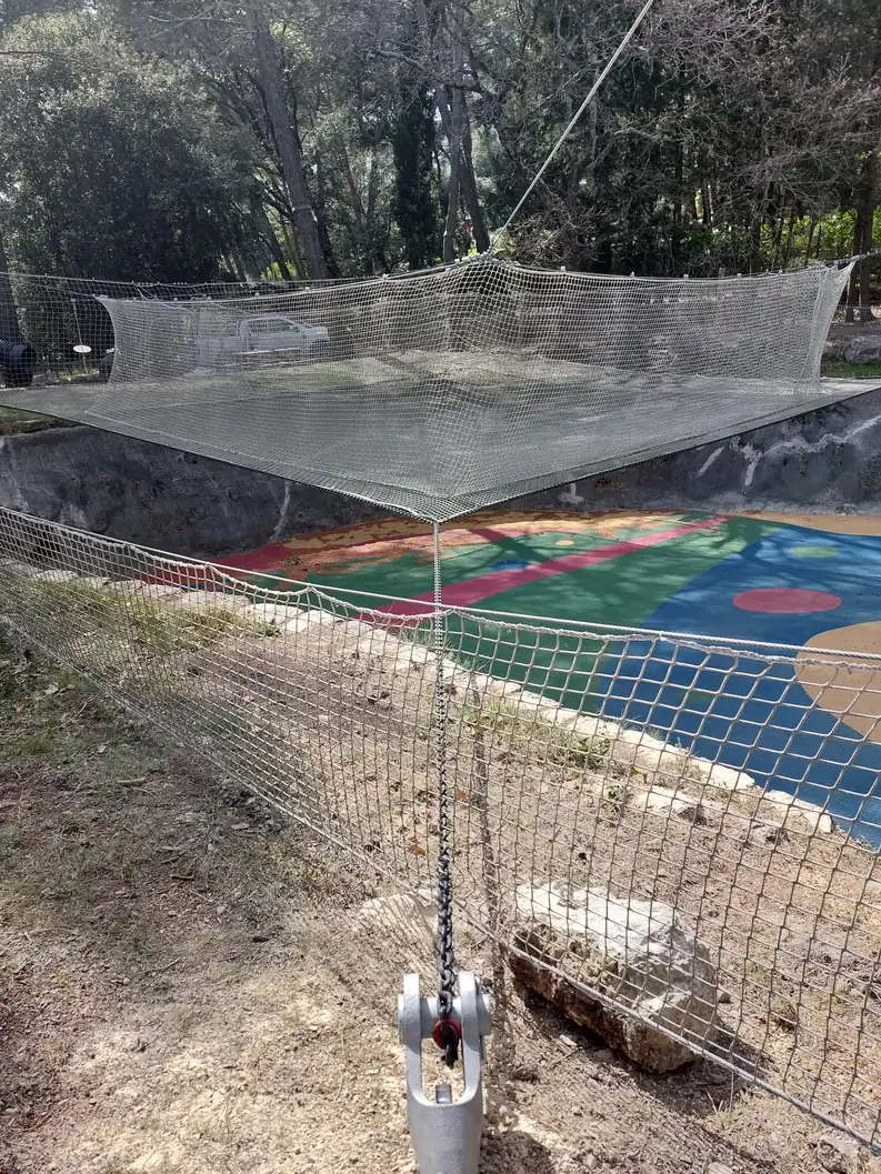 Trampoline net cage above a playground