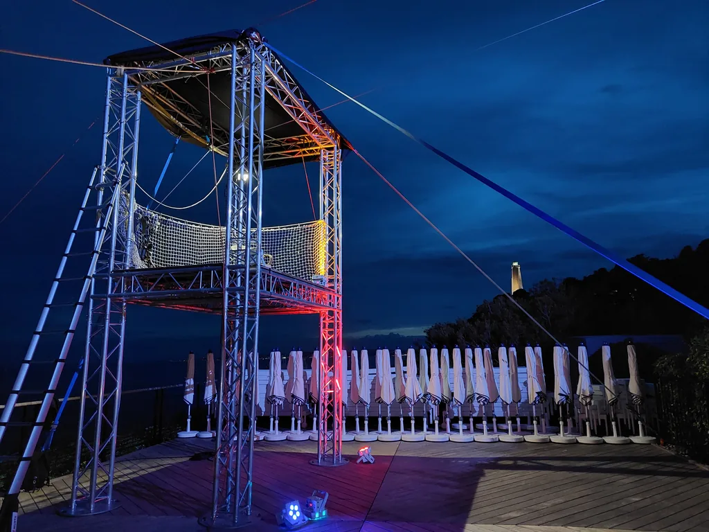 Illuminated zip line launch tower at a night-time event